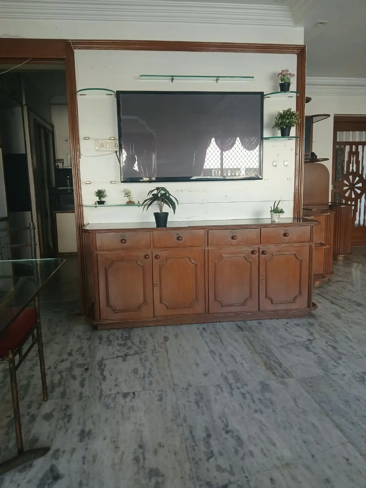 Hall with wall-mounted TV, glass shelves and wooden cabinet in a furnished 3 BHK flat, City Light, Surat