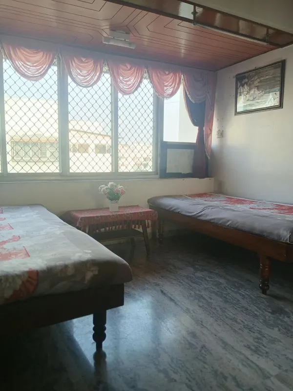 Bedroom with two single beds and a large grilled window, City Light, Surat